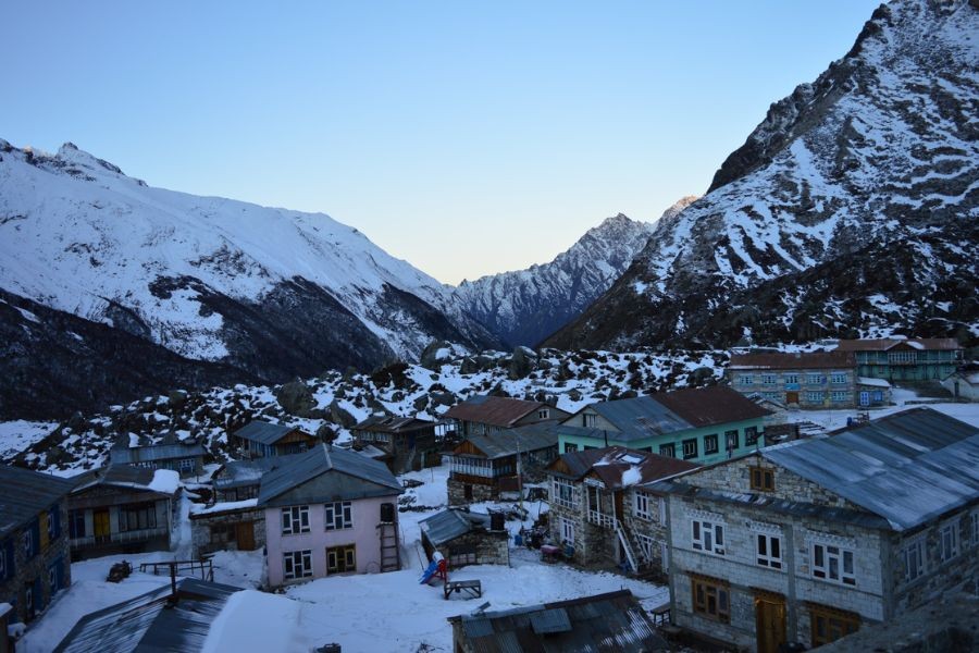 Snow-covered Langtang village with traditional stone houses nestled in the valley at sunset